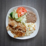 fish with onions, rice, beans, and salad on white plate