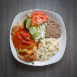 chile relleno with rice, beans and salad on a white plate